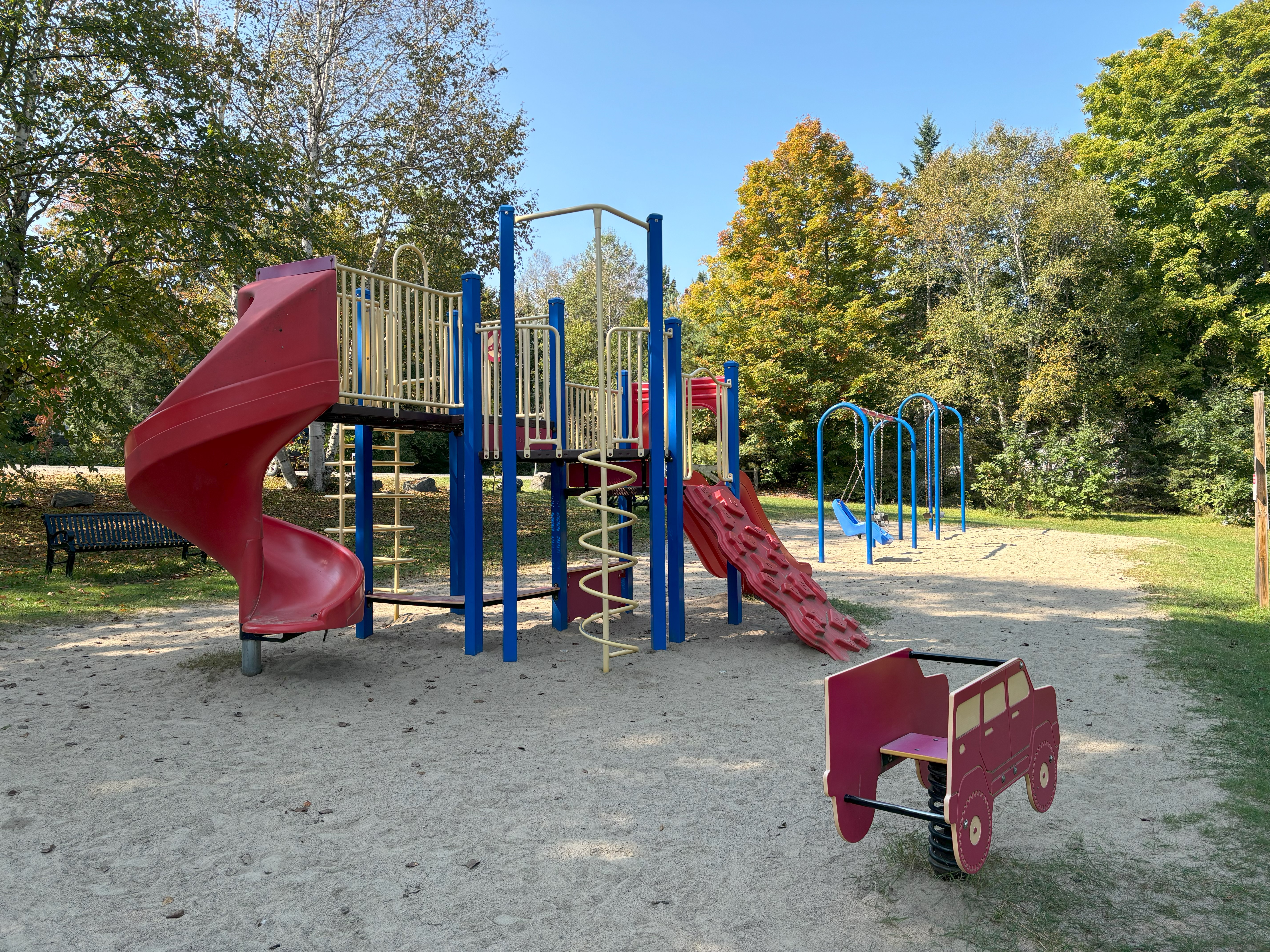 Playground equipment at Haliburton Lake red double slides, blue posts, yellow railings.